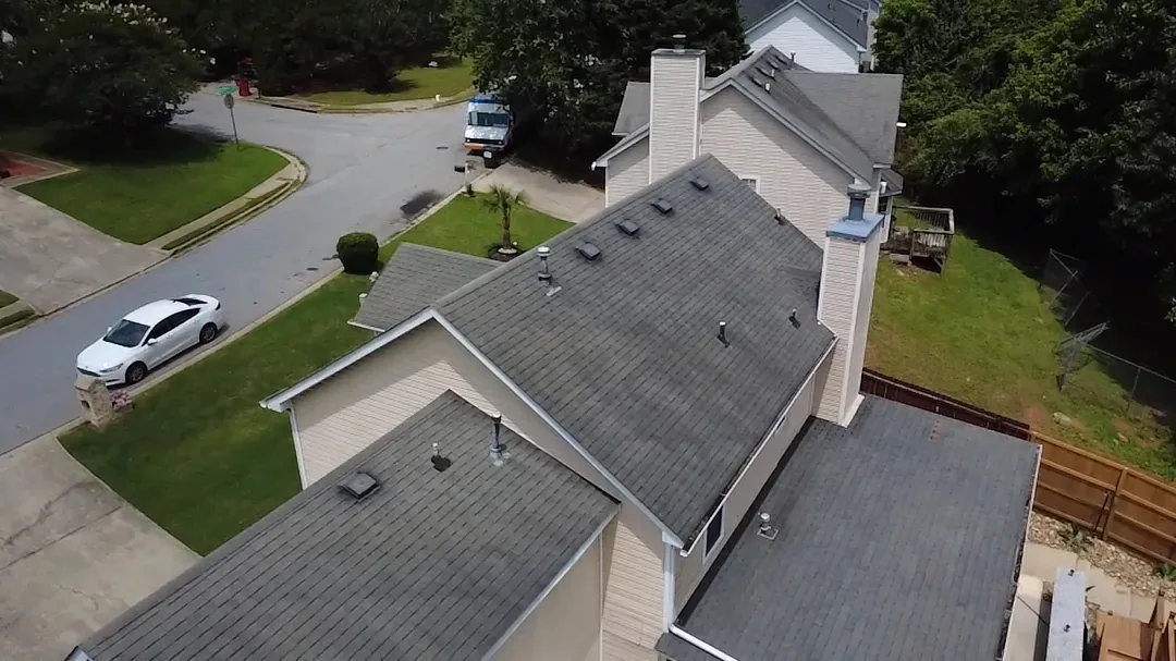 Aerial view of a two-storey home before replacement, with a faded gray shingle roof on every slope.