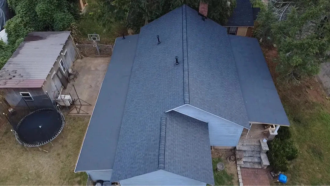 Aerial view of the finished home with new black architectural shingles on every slope.