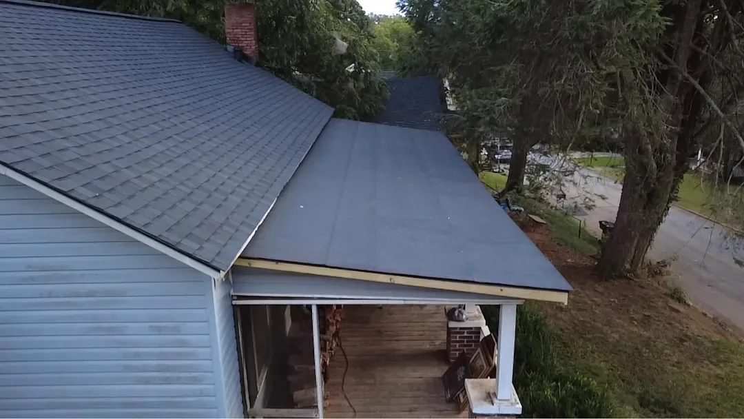 The rebuilt porch roof with a clean new edge, tied into new black architectural shingles on the main roof.