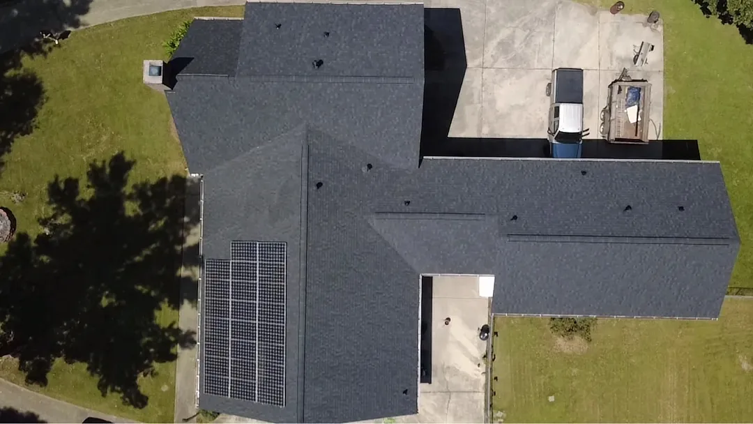 The same home from above with new dark gray architectural shingles and the solar array in place on one slope.