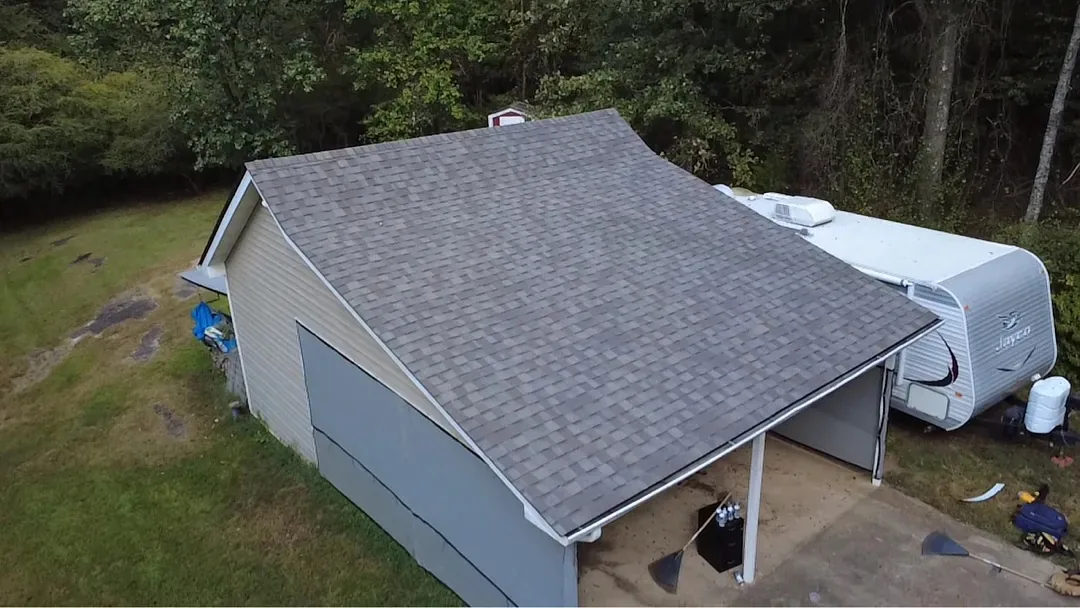The detached garage and carport at the same property with the same new shingles.